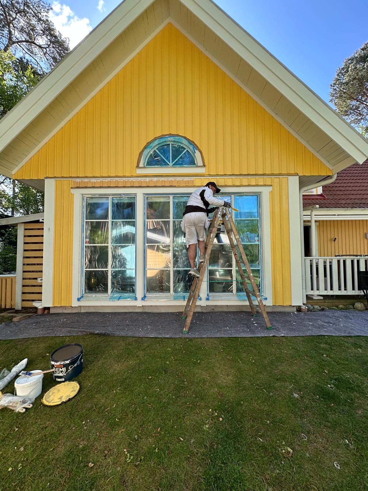 Pågående fasadmålning av träpanel